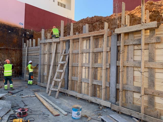 Ouvriers du bâtiment installant un coffrage en bois pour un mur sur un chantier.
